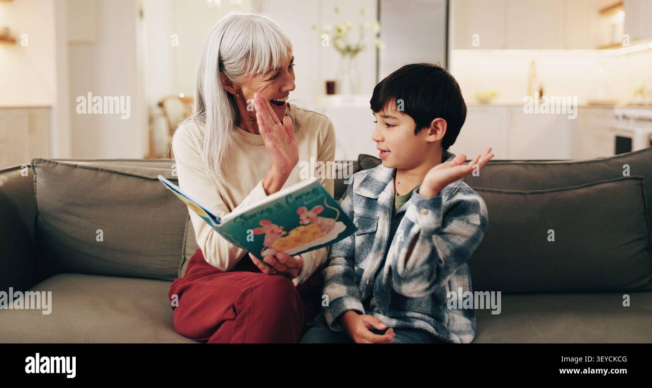 Buch, Großmutter oder Kind mit hohen fünf auf dem Sofa für einen Meilenstein der Alphabetisierung, Lernunterstützung oder Pflege. Familie, Junge oder Seniorin mit Feierlichkeiten Stockfoto