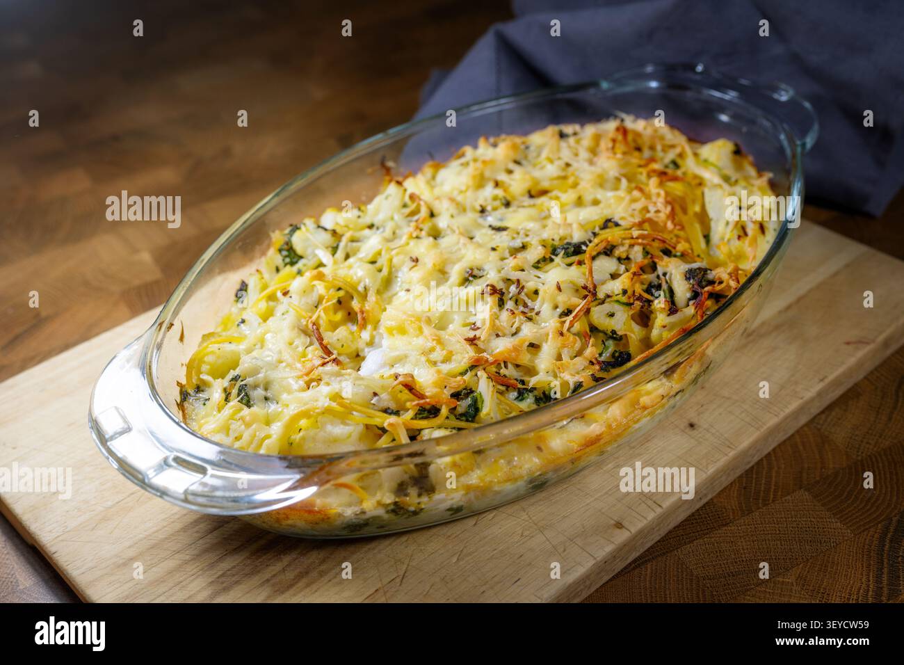 Auflauf mit Blumenkohl, Spinat und Spaghetti, gebacken mit Ei und Käse in einer Glasschale, auf einem dunklen rustikalen Holztisch, hausgemachte vegetarische Mahlzeit Stockfoto
