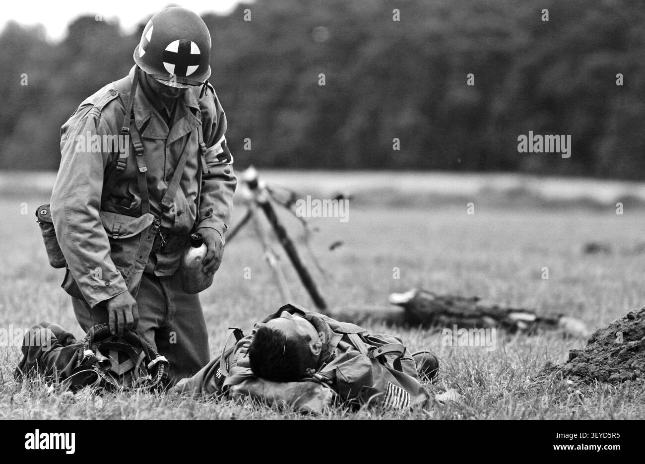 US-Armee Kämpfer aus dem Zweiten Weltkrieg kniete neben einem verwundeten Soldaten während einer historischen Nachstellung. Stockfoto
