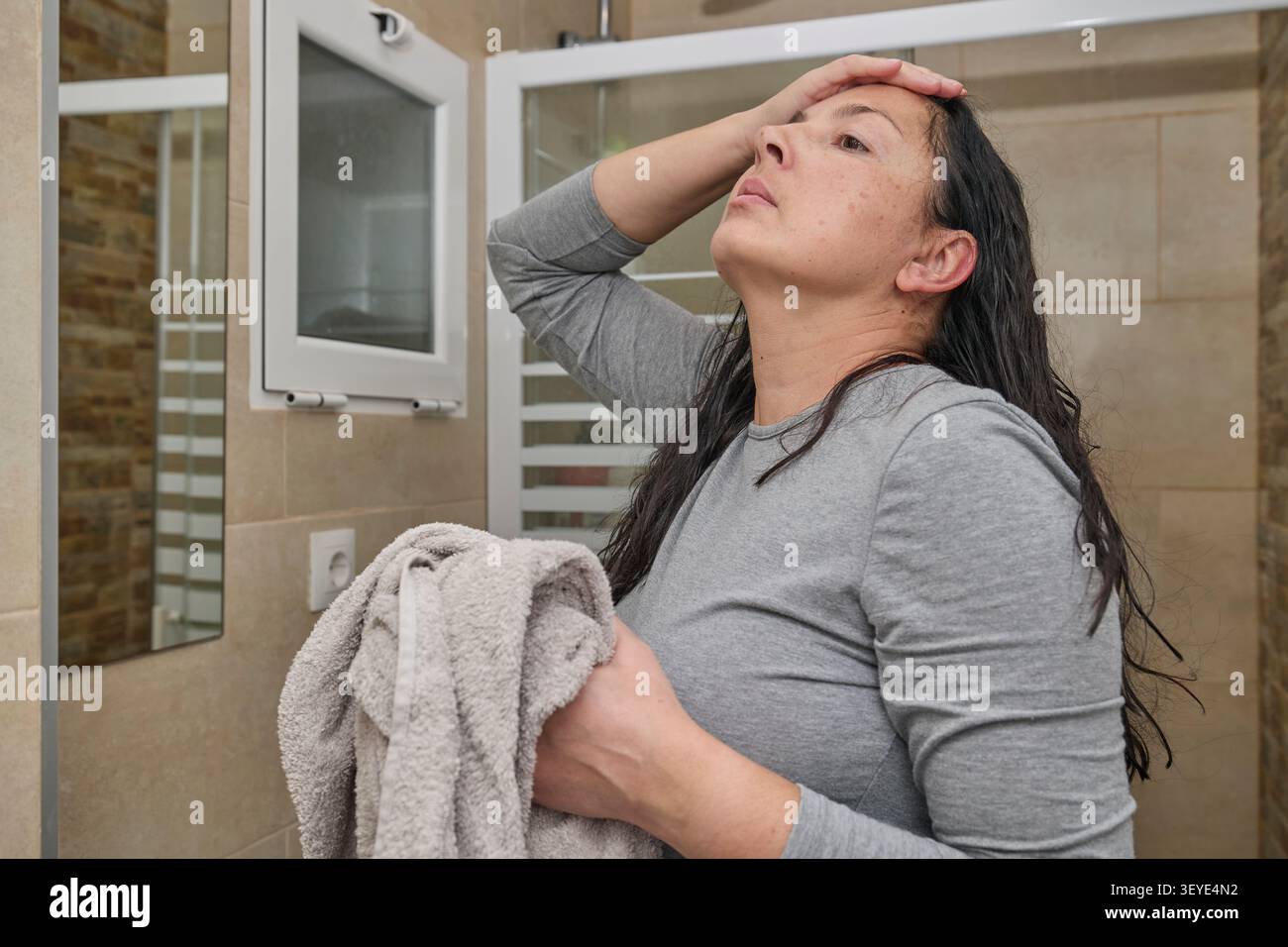 Frau im Badezimmer trocknet ihr nasses Haar mit einem Handtuch nach dem Duschen. Häusliche Pflege und Hygiene-Routine. Stockfoto