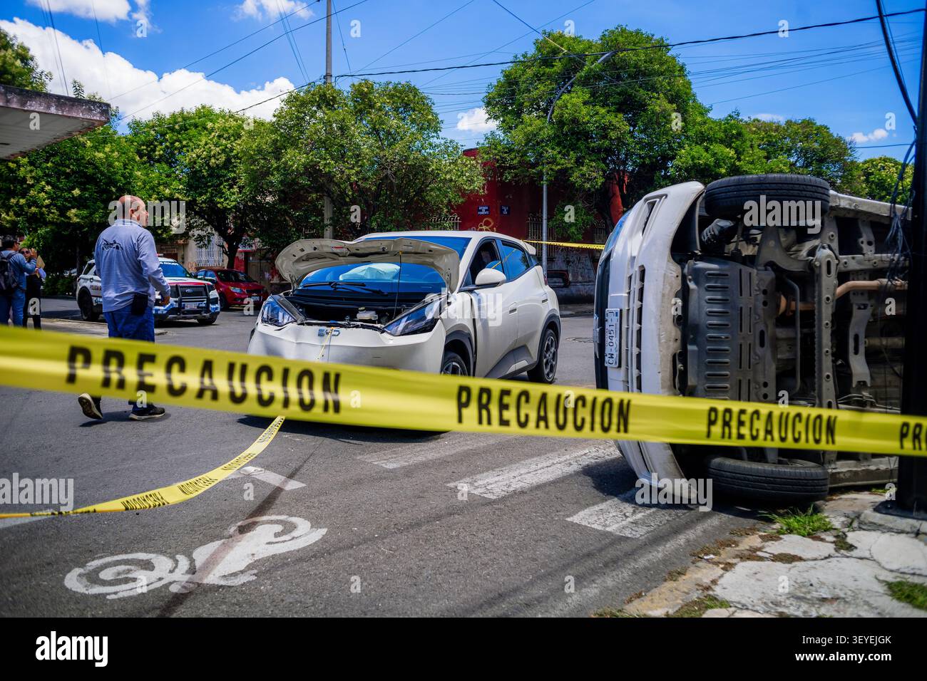 Städtischer Verkehrsunfall in Mexiko mit einem beschädigten Elektroauto und einem vollständig umgekippten Transporter auf der Seite Stockfoto
