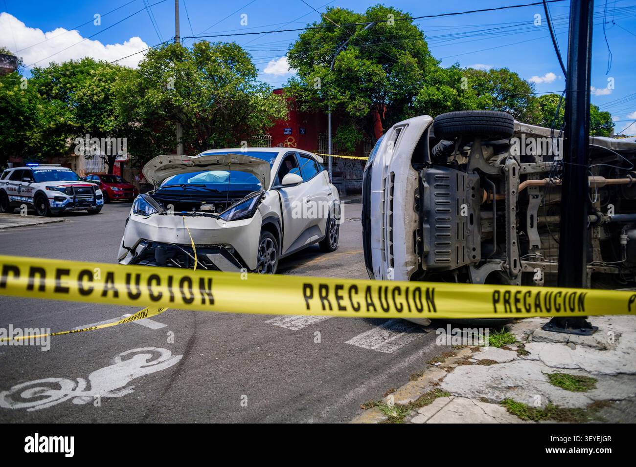 Städtischer Verkehrsunfall in Mexiko mit einem beschädigten Elektroauto und einem vollständig umgekippten Transporter auf der Seite Stockfoto