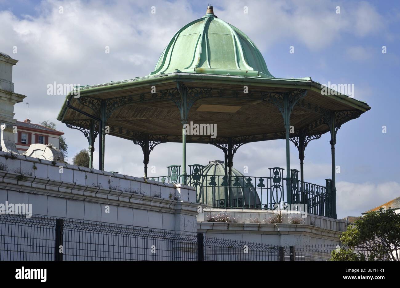 Torquay England: Kunstvoller eiserner Pavillon mit grünem Kuppeldach und kompliziertem Geländer auf einer erhöhten Plattform unter blauem Himmel Stockfoto