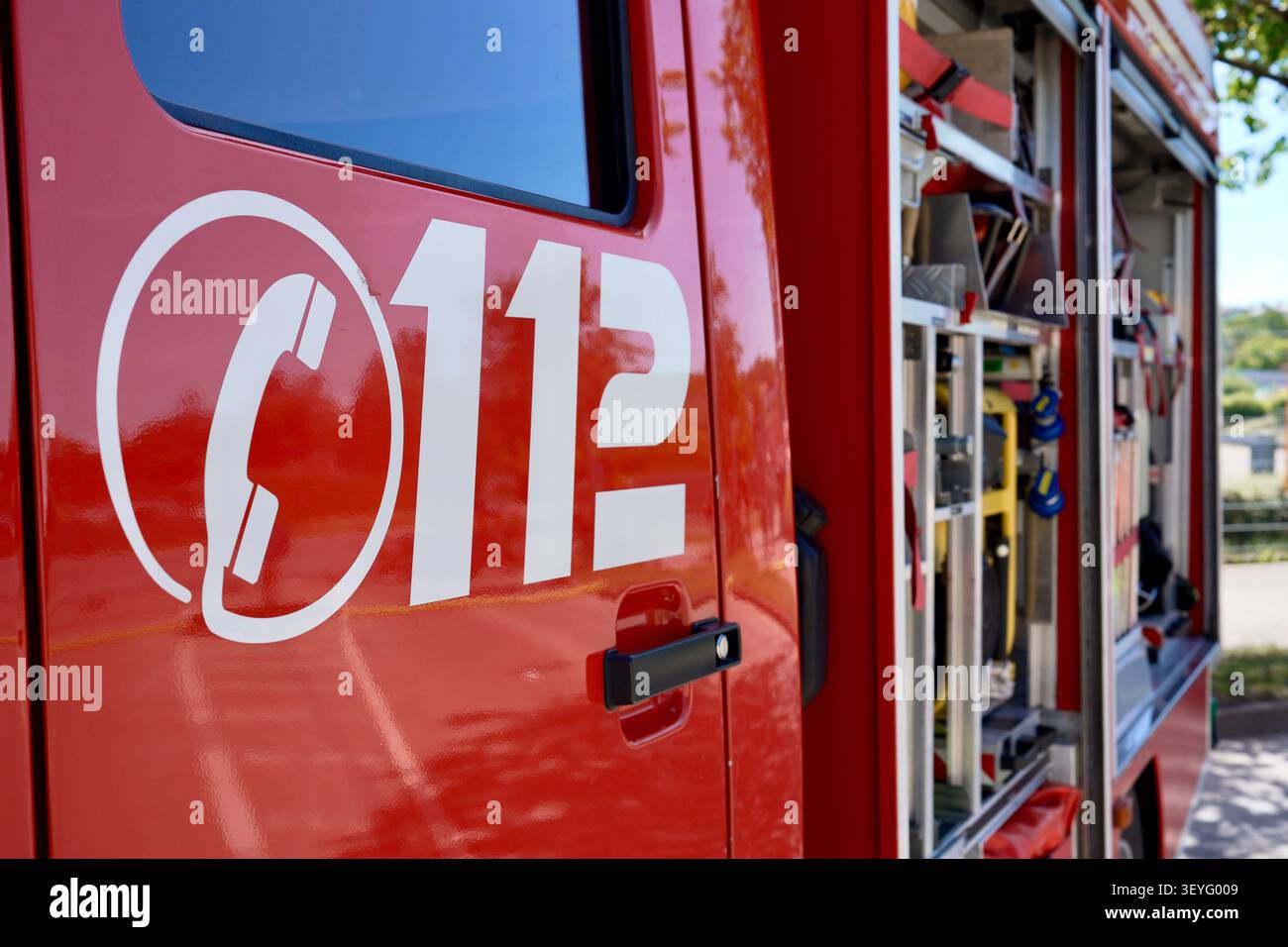 Feuerwehrfahrzeug mit offenen Geräteräumen und Notfallnummernmarkierung Stockfoto