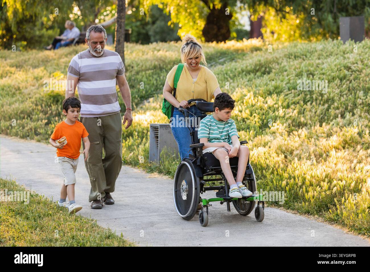 Familie einschließlich behindertengerechtem Kind, die den Spaziergang durch den Park genießen Stockfoto