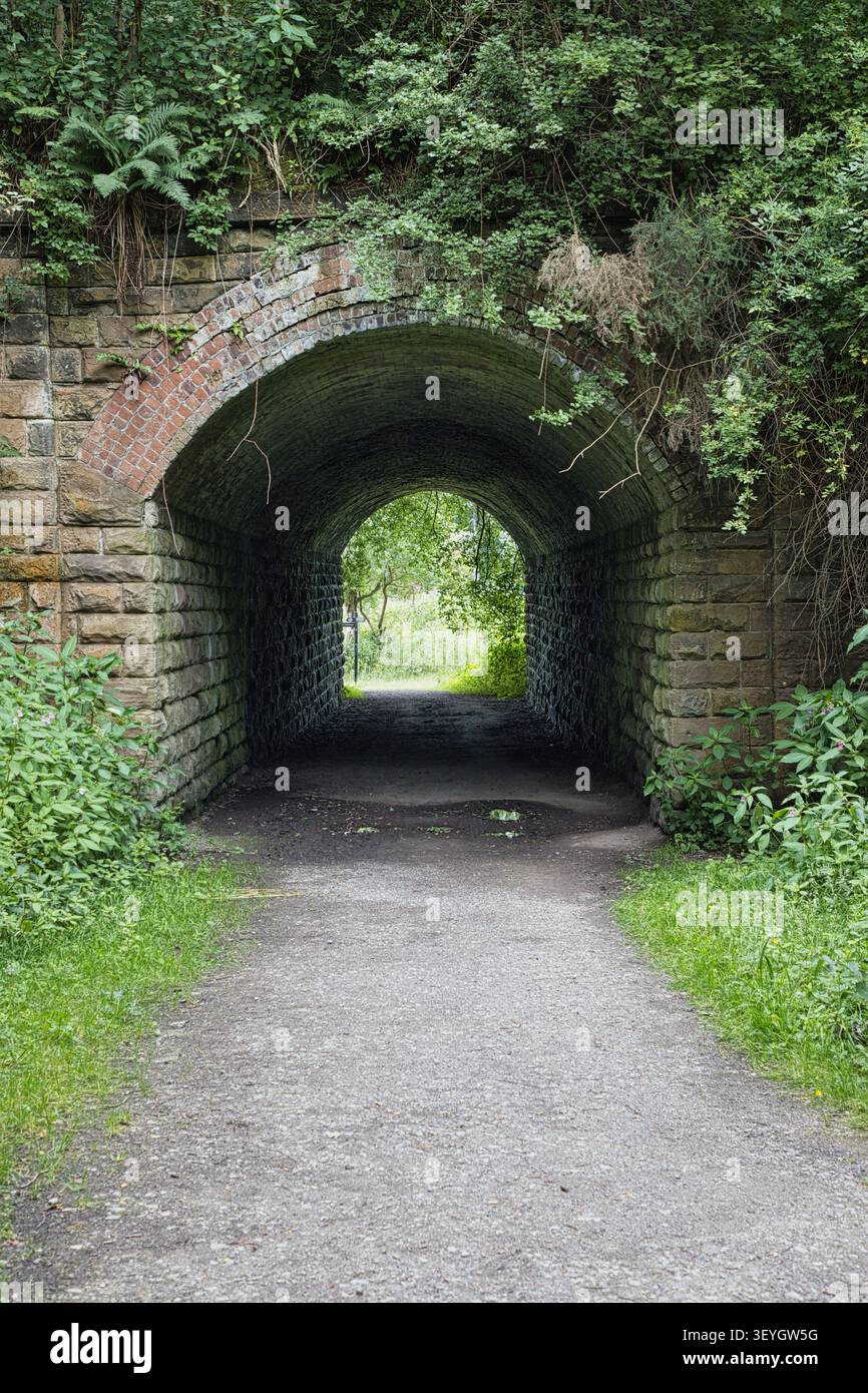 Ein alter Stein- und Ziegelbogentunnel unter einer stillgelegten Eisenbahnlinie auf einem Wanderweg in Philips Park, Whitefield, Bury, Greater Manchester, UK. Stockfoto