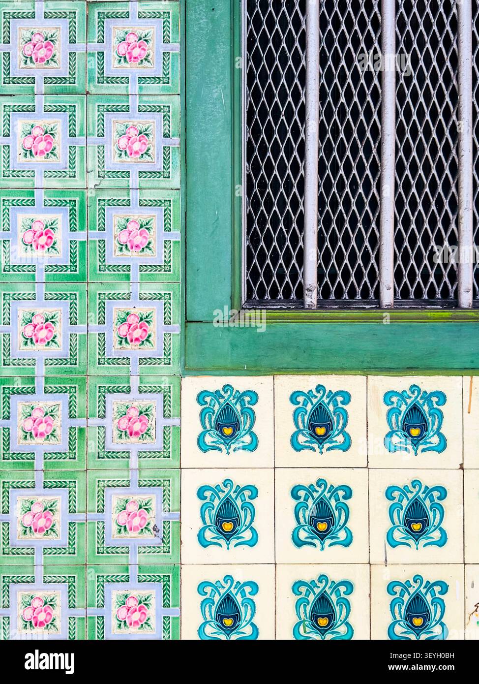 Detail traditioneller Peranakan-Keramikfliesen & grüßer Holzfensterrahmen mit Metallgitter an einer historischen Fassade in Malaysia Stockfoto