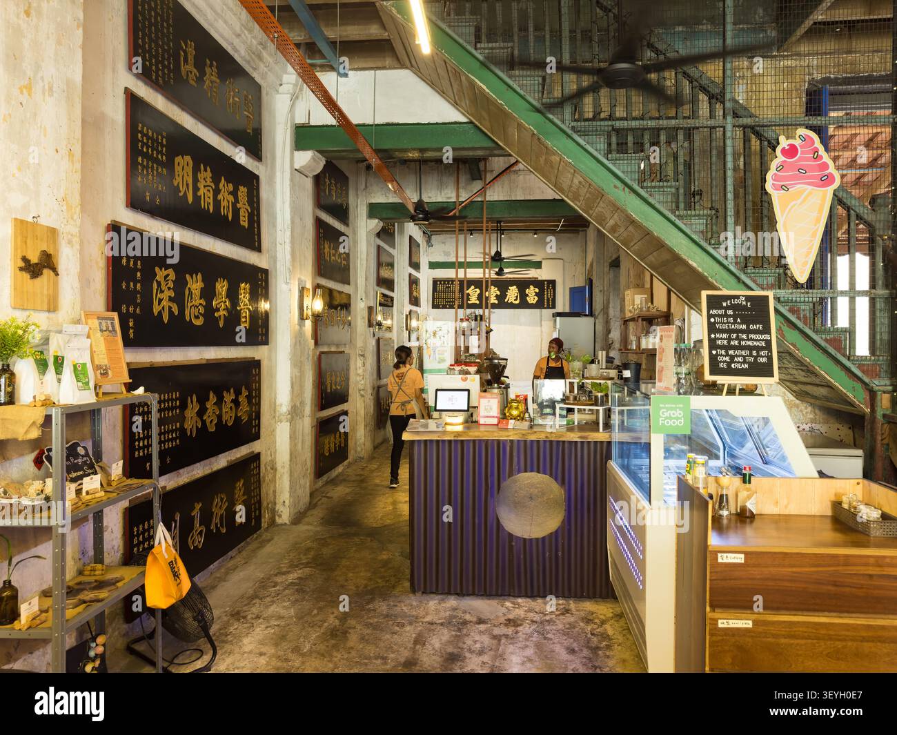 Das Innere eines rustikalen, traditionellen Cafés & vegetarischen Restaurants mit chinesischen Tafeldekorationen und einem GrabFood-Service-Theken Stockfoto