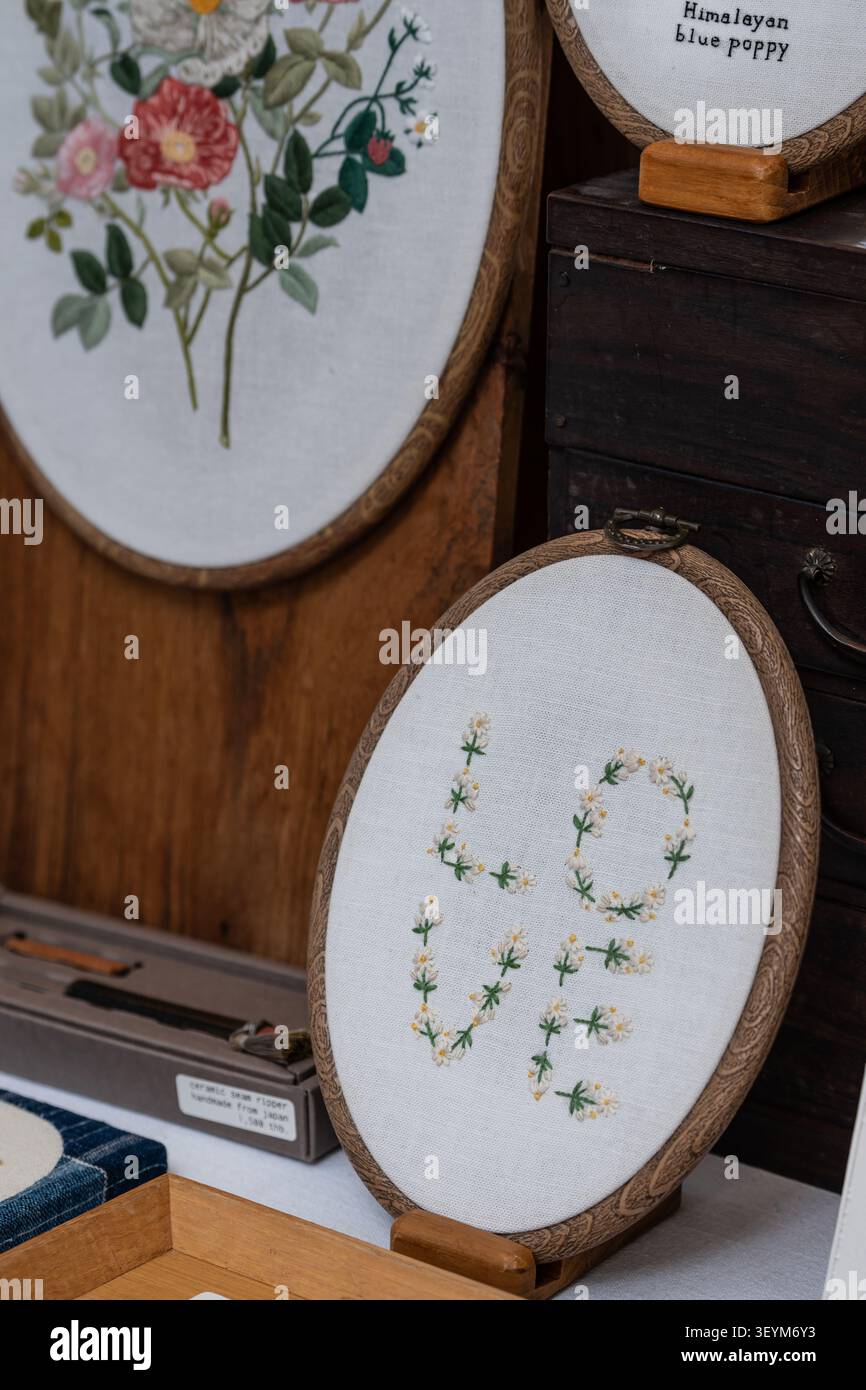 Chiang Mai, Thailand - 27. Mai 2026 : Stickerei Hoop Art Rechtschreibung LIEBE mit Blumenbuchstaben angezeigt neben Botanical Embroidery Craft Stockfoto