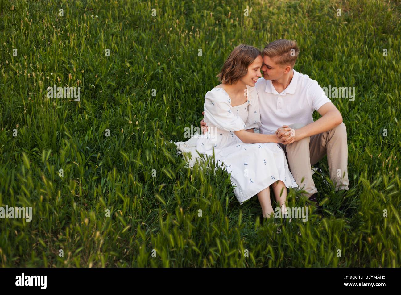 Ein romantisches Paar genießt einen friedlichen Nachmittag im Freien, eingebettet zwischen hohen Gräsern und Wildblumen Stockfoto