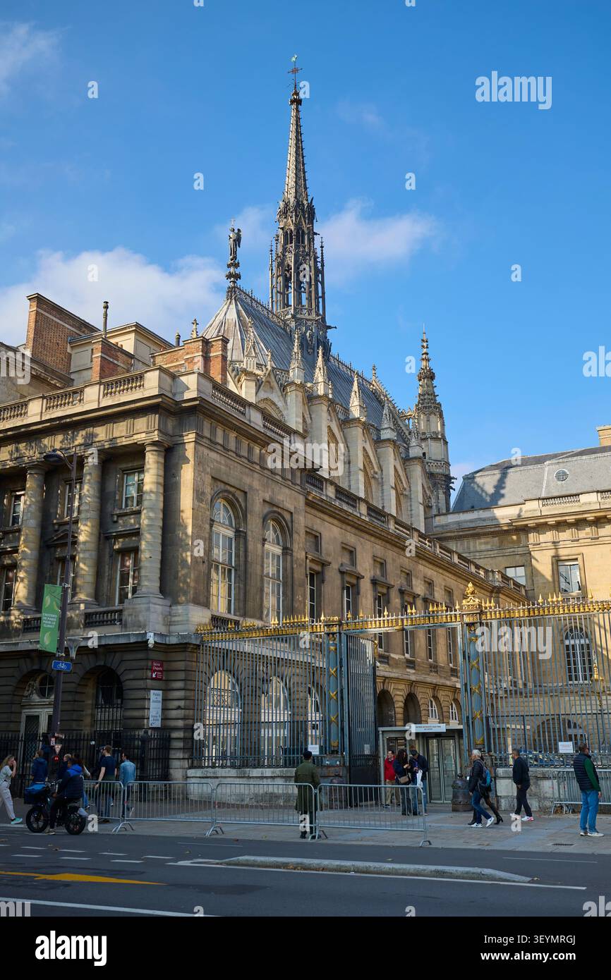 Seitenansicht der Sainte Chapelle und des Palais de Justice in Paris, Frankreich, mit Menschen, die in der Nähe der goldenen Tore und des gotischen Turms laufen. Paris, Frankreich - Oktob Stockfoto