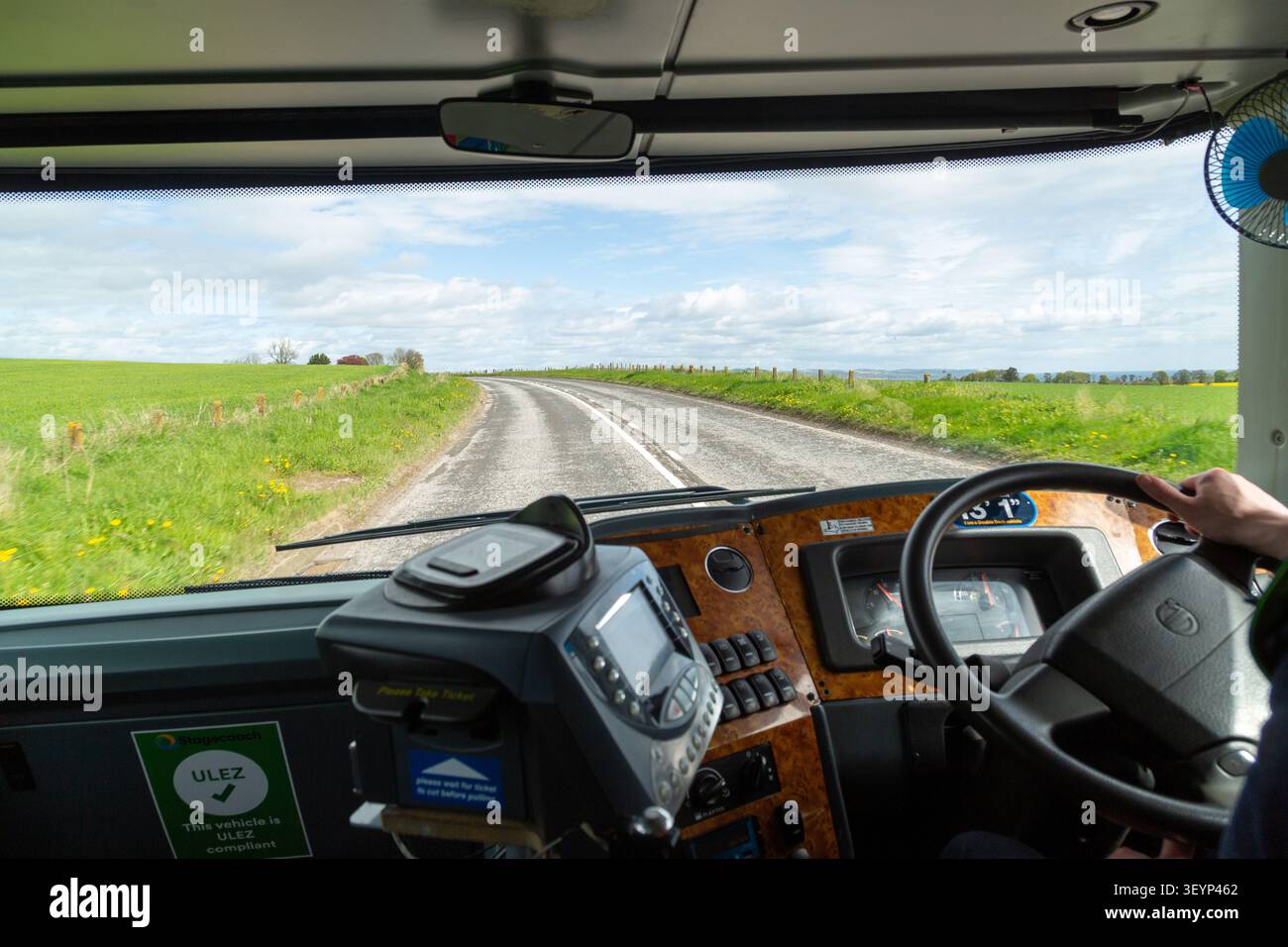 Die Sicht durch die Busfrontscheibe auf eine Landstraße vor uns, Schottland. Stockfoto