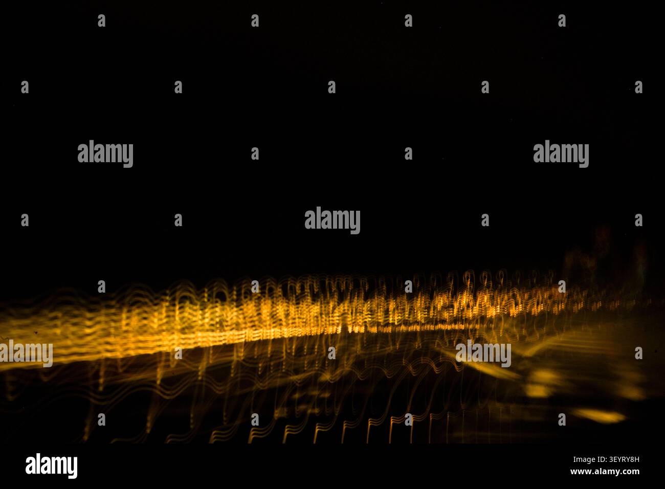 Dynamische Komposition mit zwei Lichtspuren und leuchtenden weißen Wellen und goldenen Unschärfen. Stockfoto