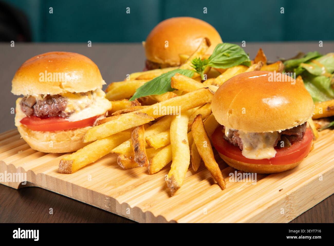 Trois Mini-Burger sont présentés avec des frites sur une Table. Stockfoto