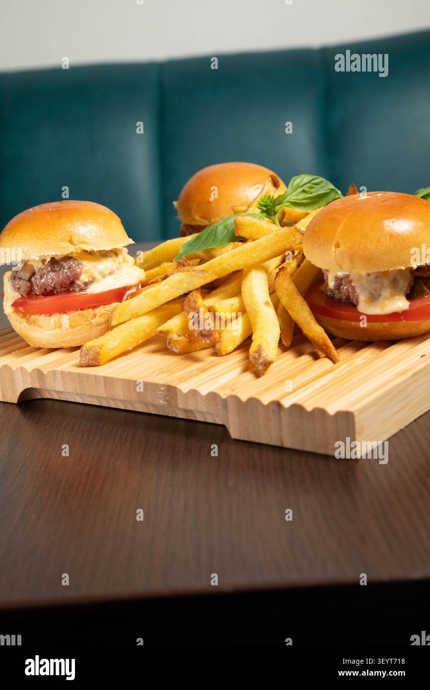 Des Mini Burgers avec de la viande et des Tomates sont servis avec des frites dans un Restaurant. Stockfoto