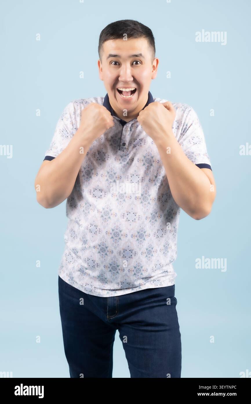 Aufgeregter junger Mann, der Hände nahe dem Mund hält und überrascht aussieht Stockfoto