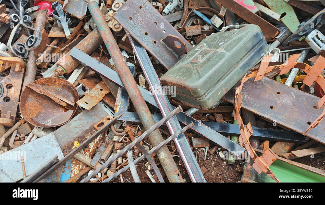 Ein Blick von oben auf einen alten olivgrünen Metallbrennstoff, den jerry zwischen einem Haufen rostiger Eisenschrott und Rohre entsorgt hat. Stockfoto