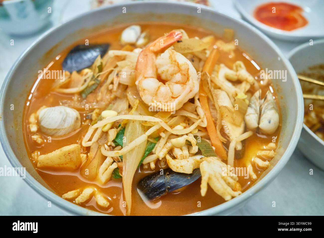 Klassisches koreanisch-chinesisches Festmahl mit herzhaften Nudeln, scharfer Meeresfrüchtesuppe und knusprigem Schweinefleisch. Highlights authentisches lokales Essen für kulinarische Reisemedien Stockfoto