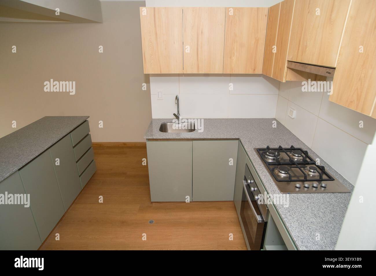 Moderne kleine Küche mit Inselarbeitsplatte, Holzschränken und offenen Regalen in einer neuen Wohnung Stockfoto