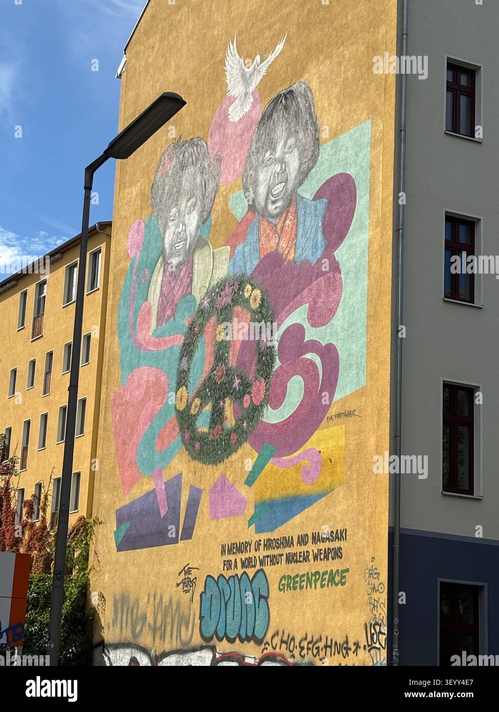 Ein großes anti-nukleares Friedensmural von Greenpeace, das auf die gelbe Fassade eines Stadtgebäudes gemalt wurde, Berlin, Deutschland - Smartphone-aufgenommenes Stockfoto