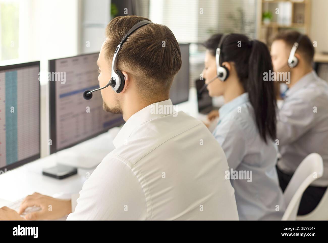 Callcenter-Betreiber mit Headsets, die an Computern in einem modernen Büro arbeiten Stockfoto