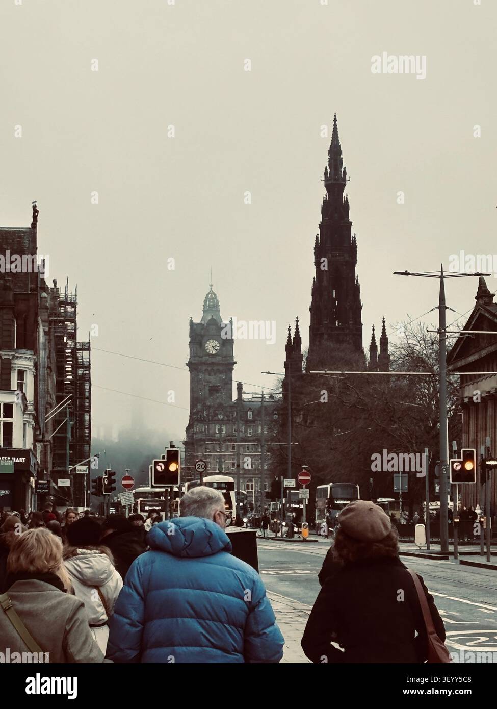 Belebte Princes Street an einem nebligen Wintertag mit Blick auf das historische Scott Monument und den Uhrturm des Balmoral Hotel, Edinburgh, Schottland - Smartphone-aufgenommenes Stockfoto
