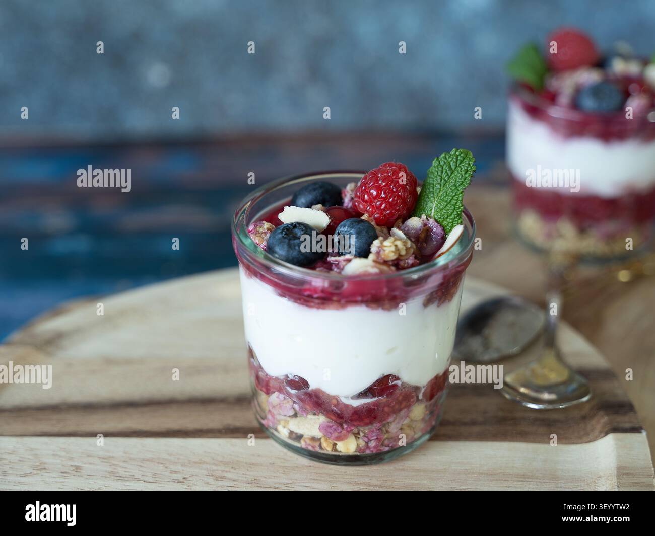Mehrschichtiges Frühstücksparfait mit Joghurt, Chiasamen, Beeren und knusprigem Müsli, serviert in einem Glas Stockfoto