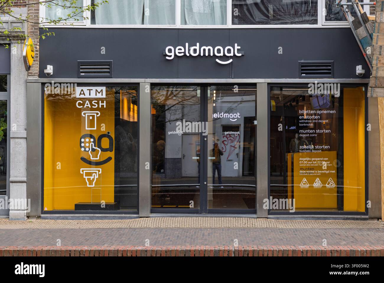 Zaandam, Niederlande - 11. April 2026: Außenansicht eines Geldmaat Geldautomaten mit gelbem Markenzeichen direkt an der Bank. Stockfoto