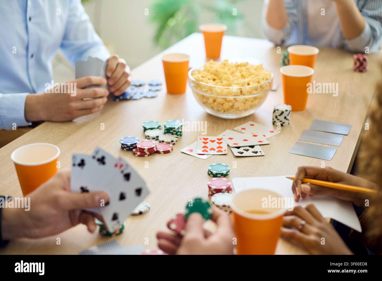 Freunde spielen Poker mit Karten und Chips am Nachttisch zu Hause mit Snacks Stockfoto