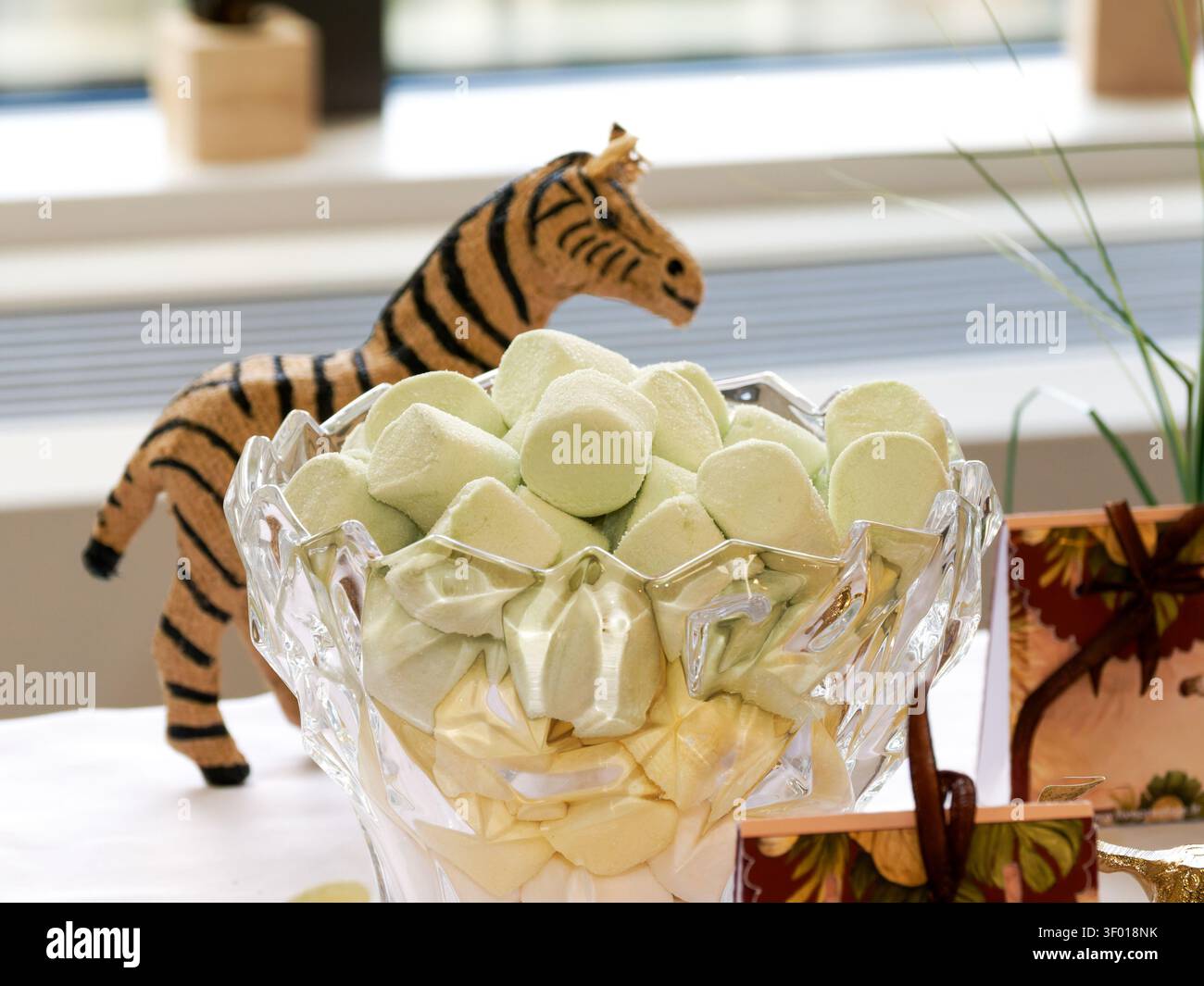 Tigerfigur, die neben einer Glas-schale mit weißen Marshmallows bei einer Dschungel-Themenveranstaltung ausgestellt ist Stockfoto