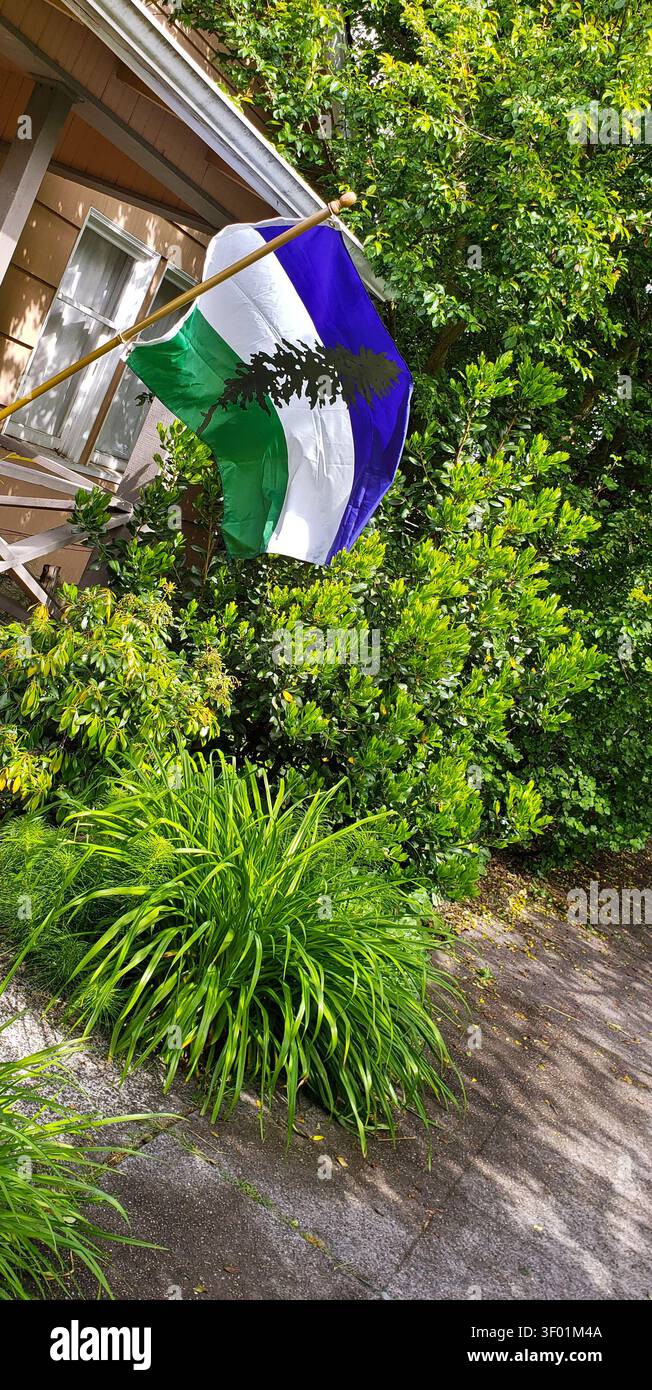 Cascadia Flag fliegt vor dem Wohnhaus im üppigen Pacific Northwest Garden Stockfoto