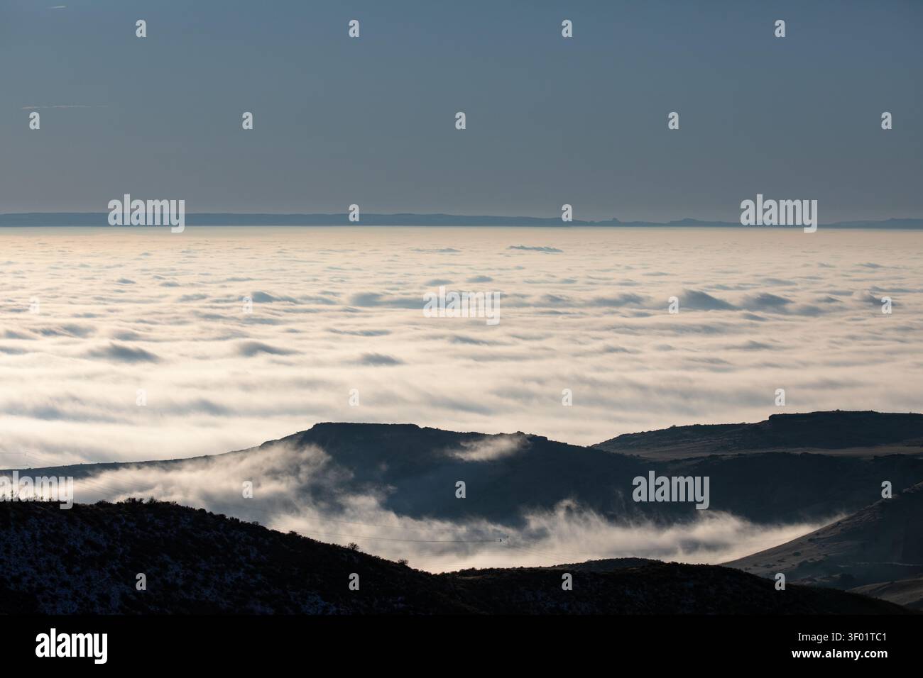 Schneebedeckte Berggipfel durchstechen Wolkenschichten Stockfoto