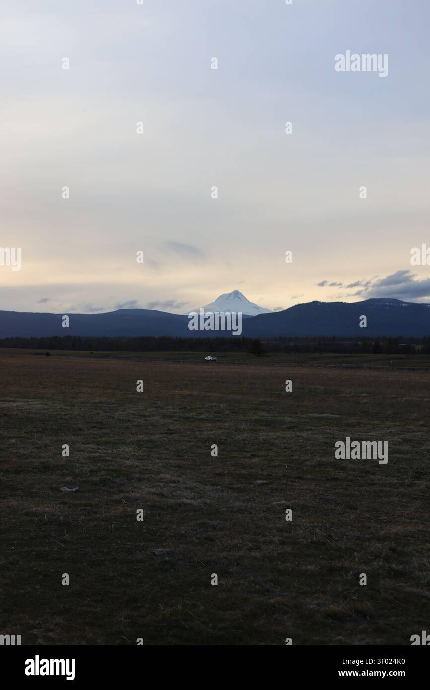 Der mächtige Mount Hood überragt in der Abenddämmerung eine dunkle ländliche Landschaft Stockfoto