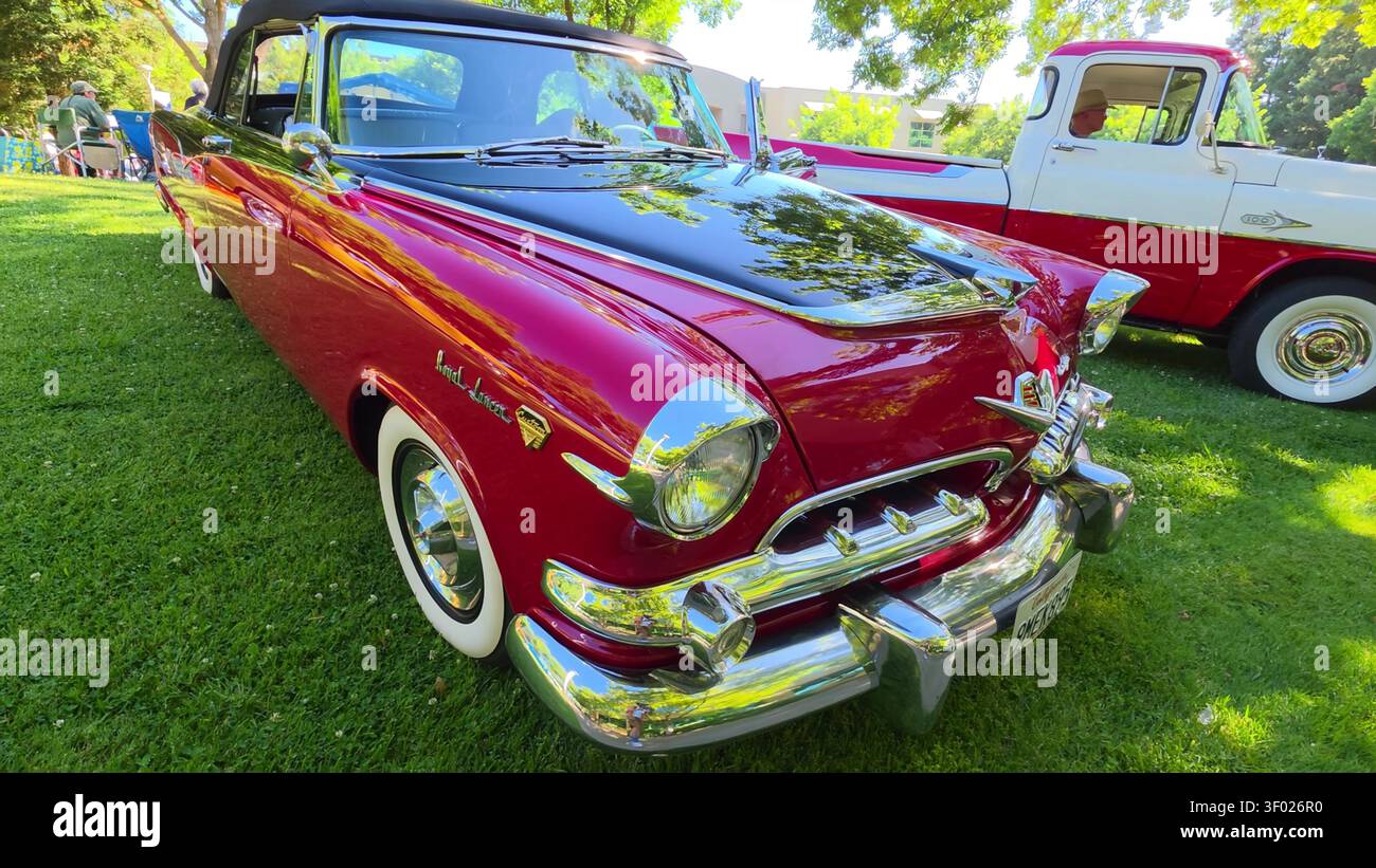 Ein zweifarbiges klassisches Cabriolet in Rot und Schwarz, das während einer Autoausstellung auf einem grünen Rasen geparkt wurde. Stockfoto