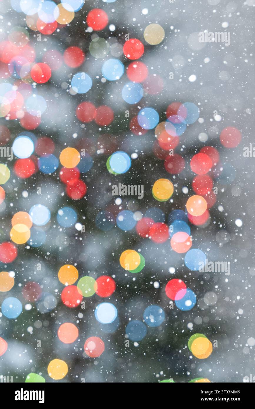 Vertikaler festlicher Hintergrund mit bunten Weihnachtsbaum-Bokeh-Lichtern auf einem sauberen weißen Hintergrund. Die sichtbare Umrisse eines Teils des Baums und sanft Stockfoto