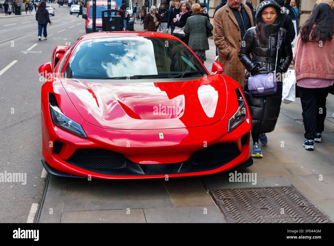 Der rote Ferrari F8 Tributo parkte auf einer Straße in der Stadt und Fußgänger laufen auf dem Bürgersteig in der Nähe Stockfoto