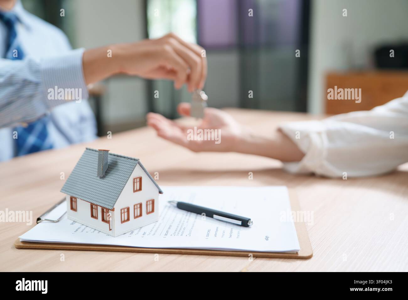 Immobilientransaktion mit Home-Modell und Schlüsseln im Dokument Stockfoto