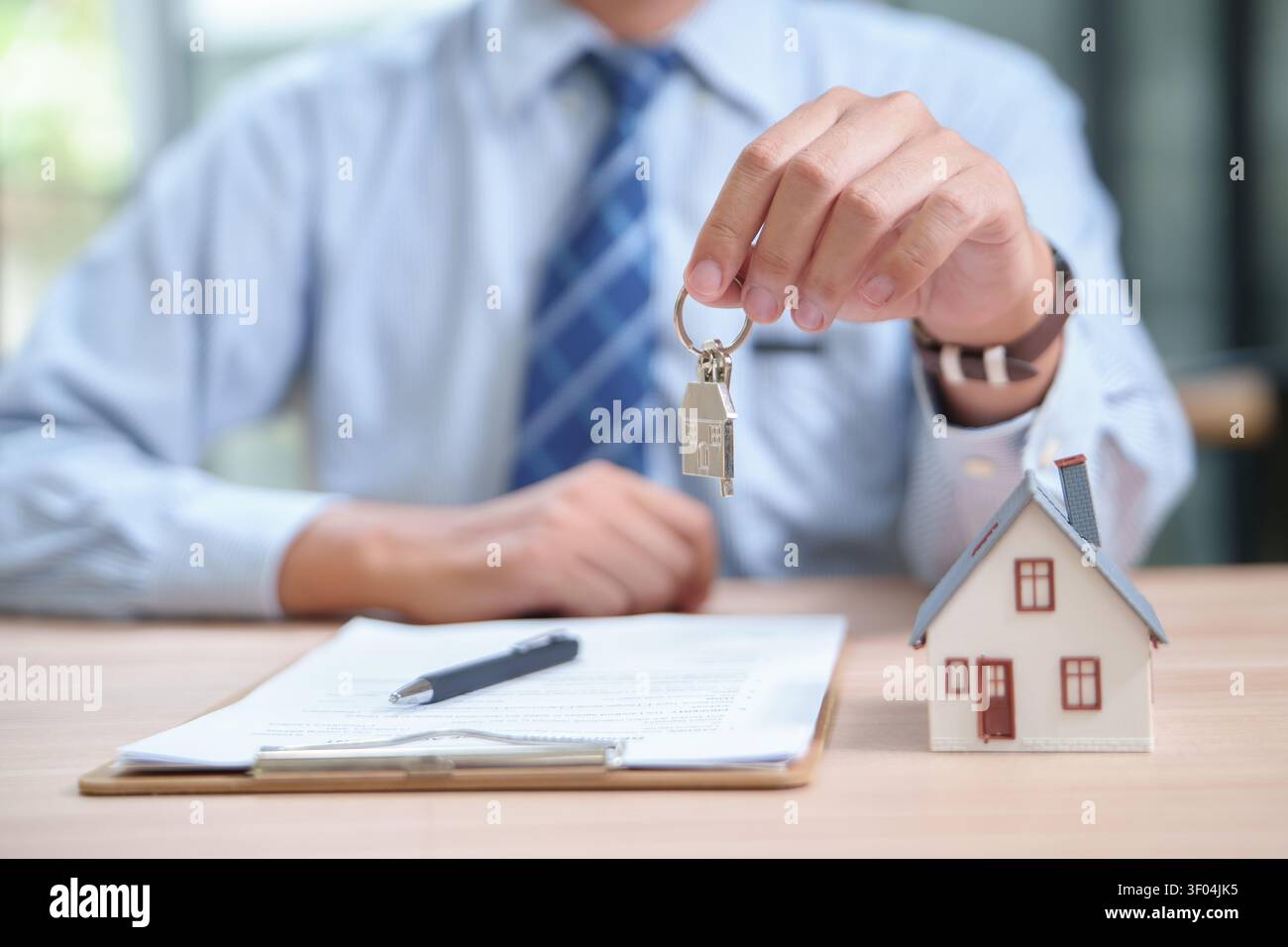 Geschäftsmann, der Schlüssel für einen Neubaukauf mit Vertrag A übergibt Stockfoto