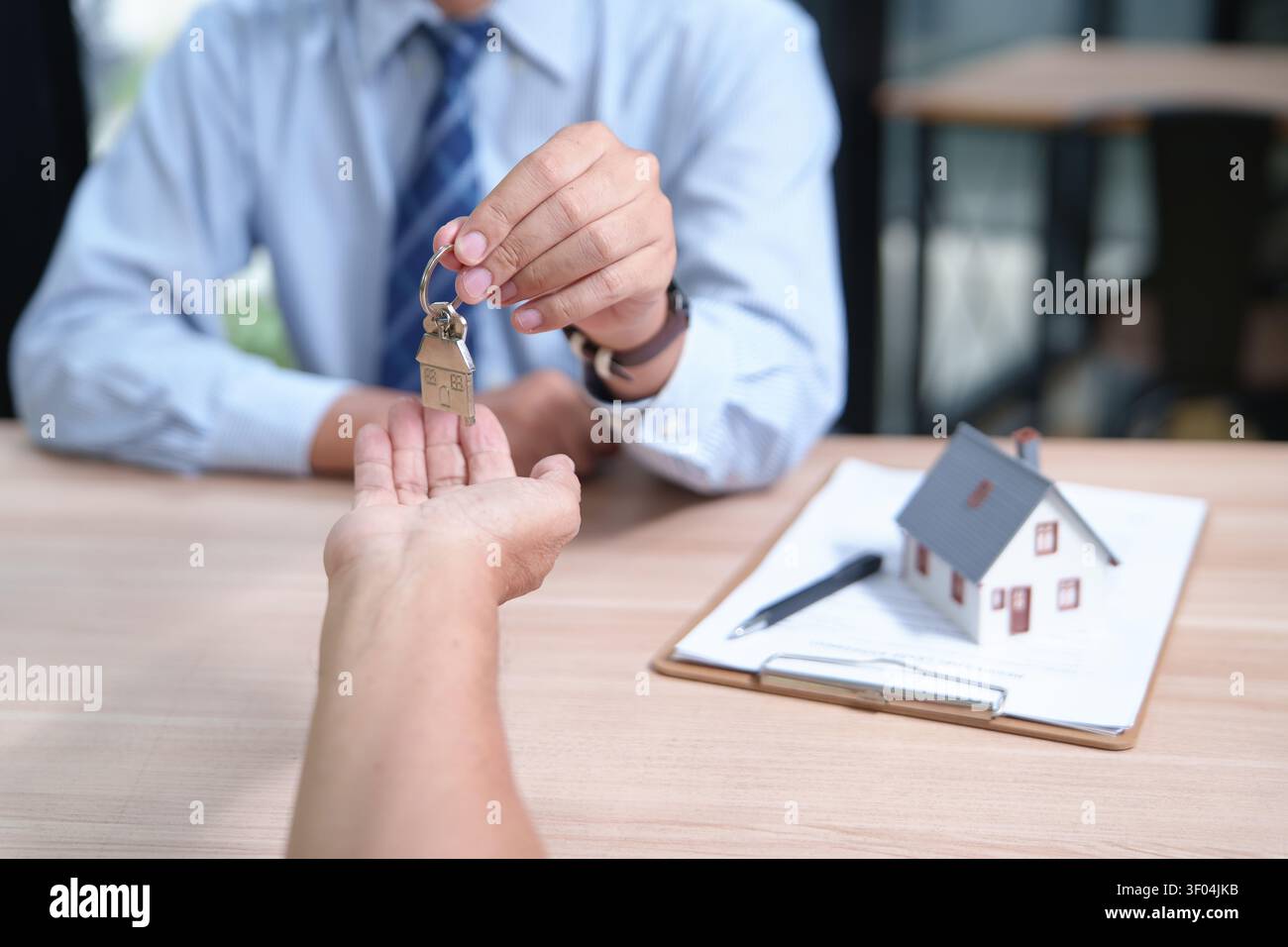 Immobilienmakler übergibt Hausschlüssel an neuen Hausbesitzer Durin Stockfoto