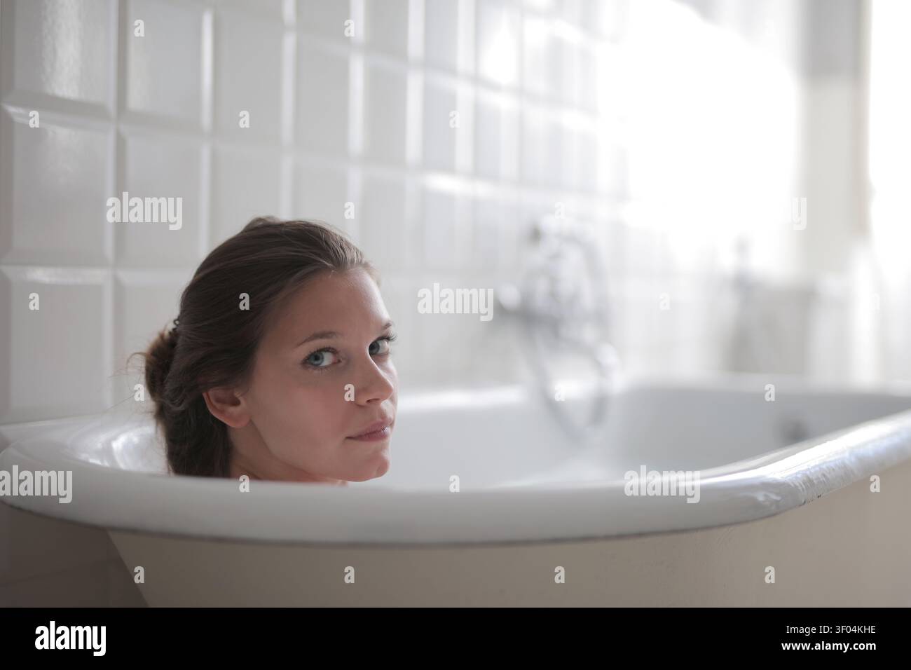 Frau, die in der Badewanne über die Schulter schaut Stockfoto