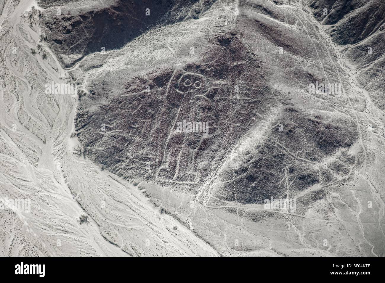 Aus der Vogelperspektive die antike Geoglyphen des Spaceman, die in die zerklüfteten Wüstenhügel der Nazca-Linien im Süden Perus gemeißelt wurden Stockfoto