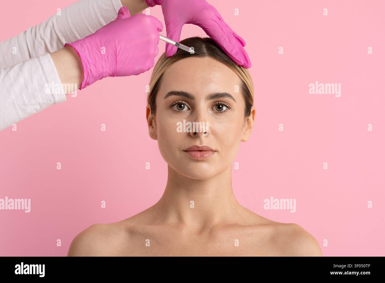 Junge schöne Frau erhält eine kosmetische Injektion in der Nähe der Stirn und des Haaransatzes Stockfoto