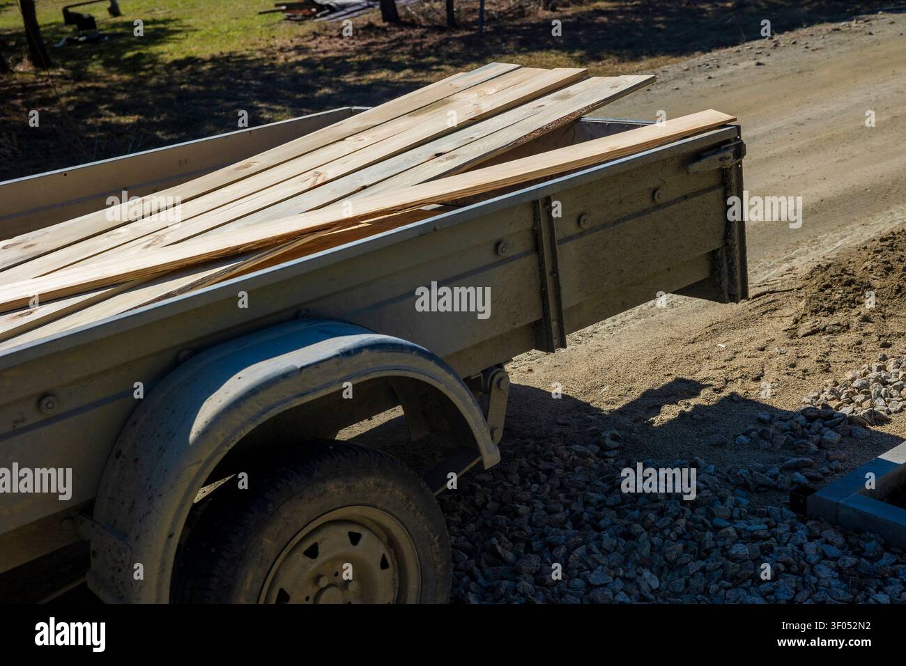 Holz, das auf einem Nutzfahrzeuganhänger entlang einer Landstraße geladen ist. Konzept: Lieferung von Baumaterialien Stockfoto