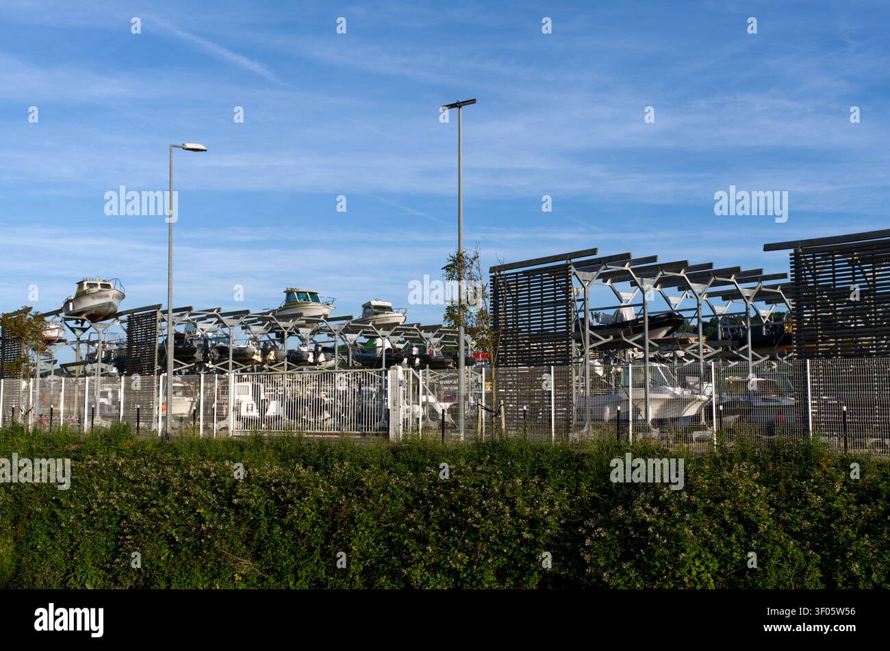Eine detaillierte Ansicht einer modernen Marina-Lageranlage mit mehrstufigen Metallregalen, die verschiedene Boote in einer organisierten vertikalen Anordnung halten. Stockfoto