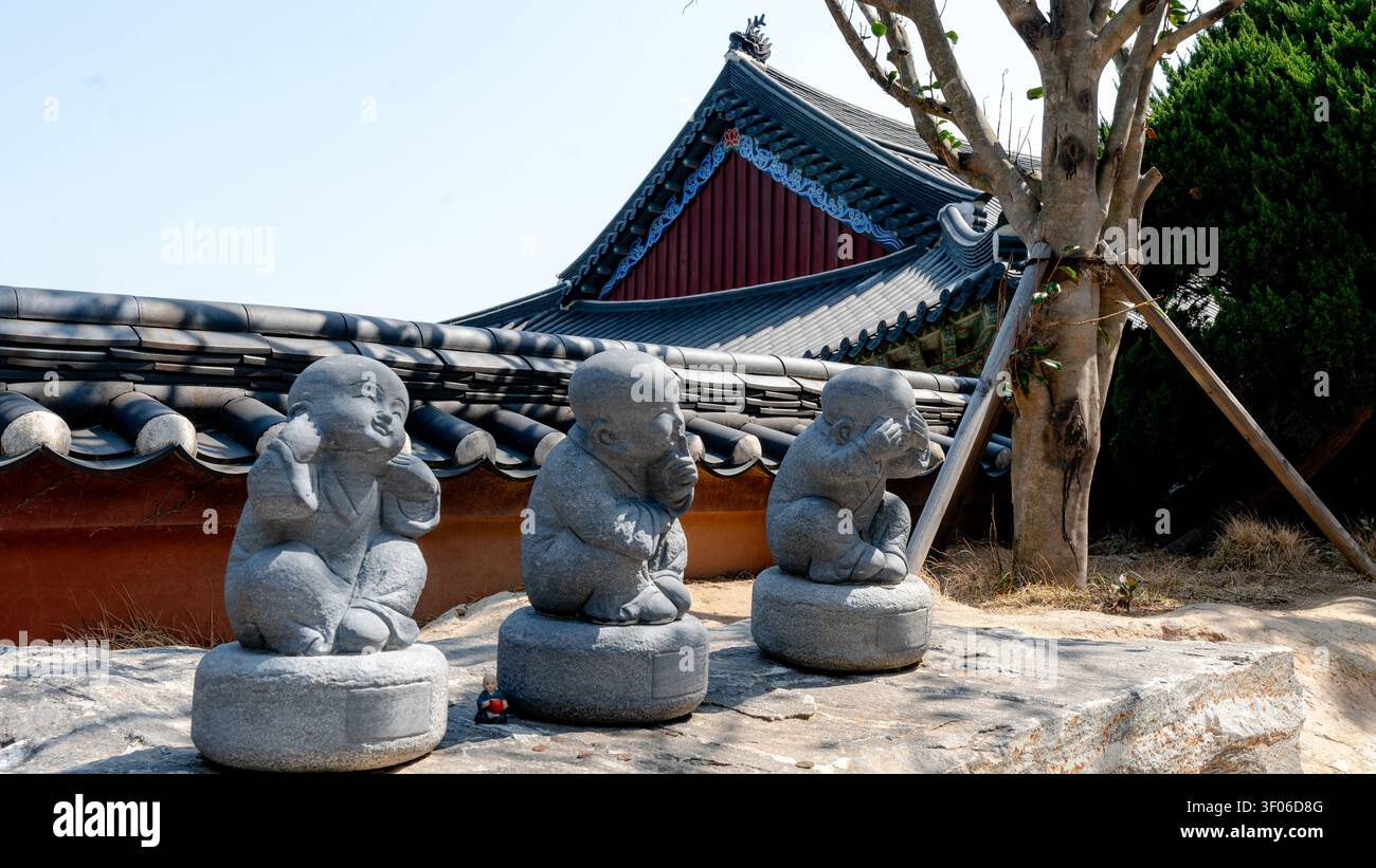 Steinstatuen von drei kleinen Buddhas, die die drei Weisen Affen darstellen, verkörpern die „See no Böse“, „Hear no Böse“, „Speak no Böse“-Konzept, bei Haeundae Stockfoto