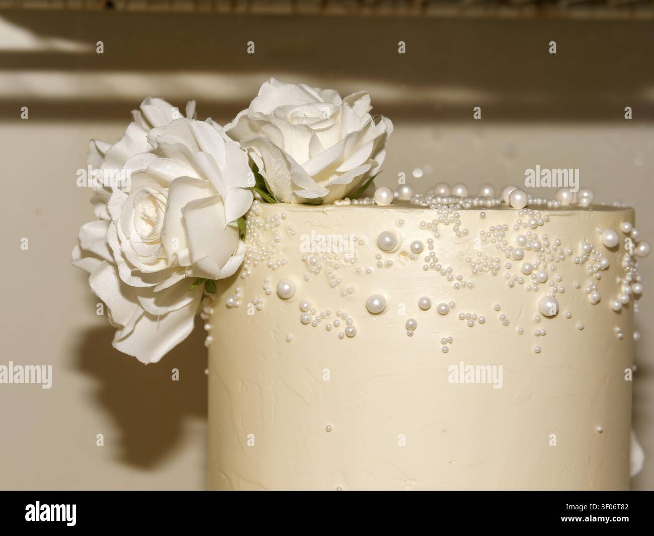 Eleganter weißer Hochzeitstorte verziert mit Zuckerperlen und weißen Rosen Stockfoto
