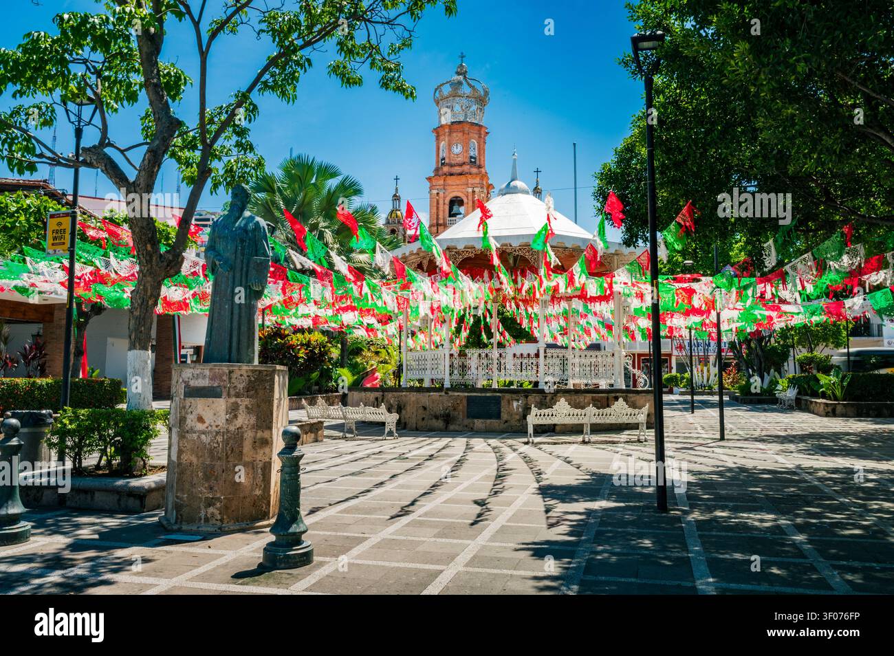 Farbenfroher öffentlicher Platz in Puerto Vallarta, Mexiko, geschmückt mit roten, weißen und grünen Papel-Picado-Bannern zur Feier der mexikanischen Nationalfeiertage. Ein Br Stockfoto