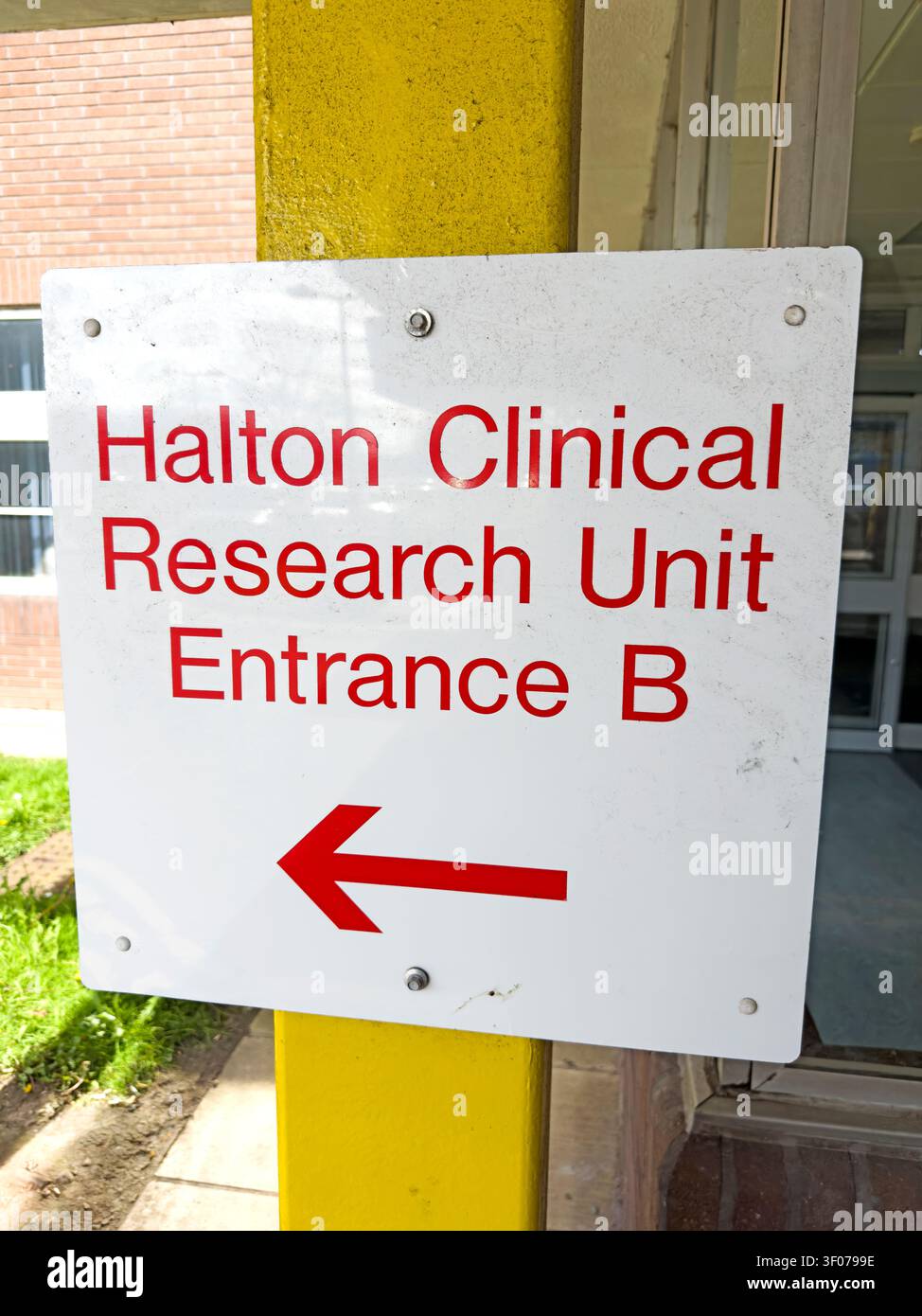 Schild, das Besucher zum Eingang B der Halton Clinical Research Unit im Halton Hospital in Runcorn, Cheshire, England, UK führt Stockfoto
