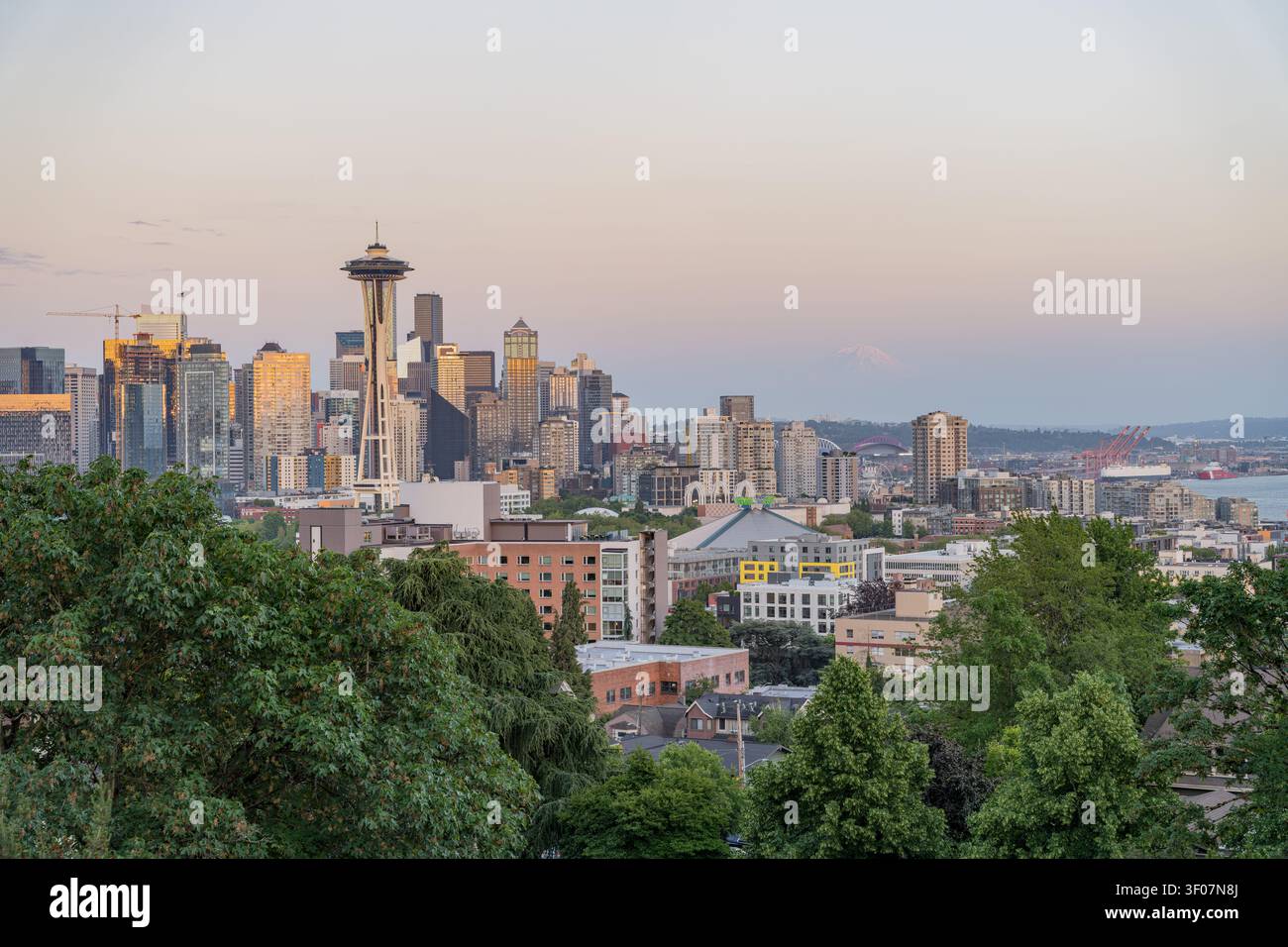Panoramablick auf die Skyline der Innenstadt von Seattle mit Mount Rainier im Hintergrund, mit Wolkenkratzern und Stadtlandschaft während der farbenfrohen Abendstunden Stockfoto
