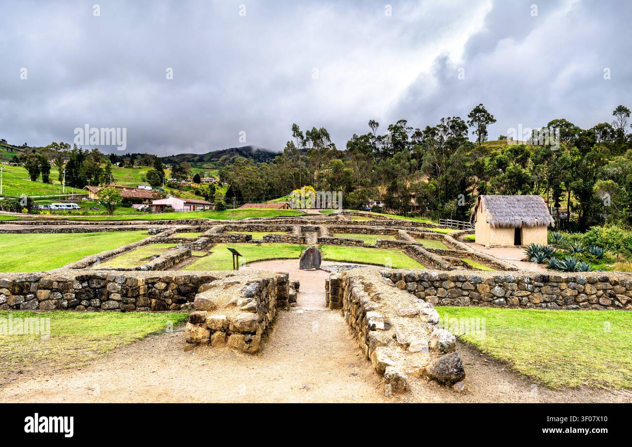 Steinruinen und traditionelle Strohhütte an der archäologischen Stätte Ingapirca in Ecuador unter bewölktem Himmel. Stockfoto